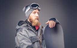 Βάναυσο redhead snowboarder με μια πλήρη γενειάδα σε ένα χειμερινό καπέλο και προστατευτικά γυαλιά που ντύνονται σε ένα snowboard στοκ φωτογραφία με δικαίωμα ελεύθερης χρήσης Βάναυσο redhead snowboarder με μια πλήρη γενειάδα σε ένα χειμερινό καπέλο και προστατευτικά γυαλιά που ντύνονται σε ένα snowboard στοκ φωτογραφία με δικαίωμα ελεύθερης χρήσης