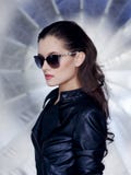 Βέβαιο και προκλητικό brunette με το όμορφο πρόσωπο, τα μοντέρνα γυαλιά ηλίου, το μαύρους σακάκι δέρματος και τον επαναστάτη hair στοκ φωτογραφίες με δικαίωμα ελεύθερης χρήσης Βέβαιο και προκλητικό brunette με το όμορφο πρόσωπο, τα μοντέρνα γυαλιά ηλίου, το μαύρους σακάκι δέρματος και τον επαναστάτη hair στοκ φωτογραφίες με δικαίωμα ελεύθερης χρήσης