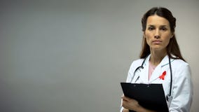 Βέβαιος γιατρός με την κόκκινη κορδέλλα που εξετάζει τη κάμερα, έννοια στοκ φωτογραφία με δικαίωμα ελεύθερης χρήσης Βέβαιος γιατρός με την κόκκινη κορδέλλα που εξετάζει τη κάμερα, έννοια στοκ φωτογραφία με δικαίωμα ελεύθερης χρήσης