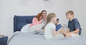 Βίντεο μαγνητοσκόπησης γονέων γέλιου των παιδιών που κάθονται μαζί στο κρεβάτι στην κρεβατοκάμαρα που μιλά, ευτυχής χρόνος οικογε απόθεμα βίντεο Βίντεο μαγνητοσκόπησης γονέων γέλιου των παιδιών που κάθονται μαζί στο κρεβάτι στην κρεβατοκάμαρα που μιλά, ευτυχής χρόνος οικογε απόθεμα βίντεο