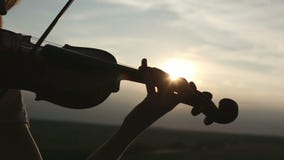 Βιολιστής κοριτσιών σκιαγραφιών που παίζει το βιολί στο υπόβαθρο ουρανού ηλιοβασιλέματος απόθεμα βίντεο Βιολιστής κοριτσιών σκιαγραφιών που παίζει το βιολί στο υπόβαθρο ουρανού ηλιοβασιλέματος απόθεμα βίντεο