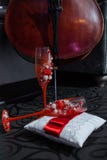 Βιολοντσέλο και δύο κόκκινα wineglasses στο μαξιλάρι στοκ εικόνες με δικαίωμα ελεύθερης χρήσης Βιολοντσέλο και δύο κόκκινα wineglasses στο μαξιλάρι στοκ εικόνες με δικαίωμα ελεύθερης χρήσης