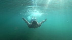 Βουτώντας, ο νεαρός άνδρας κολυμπά κάτω από το νερό με τα μάτια ανοικτά και το φωτεινό φως του ήλιου διαπερνά φιλμ μικρού μήκους Βουτώντας, ο νεαρός άνδρας κολυμπά κάτω από το νερό με τα μάτια ανοικτά και το φωτεινό φως του ήλιου διαπερνά φιλμ μικρού μήκους