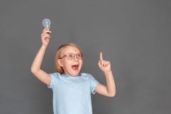 βρήκε το διάλυμα Μικρό κορίτσι eyeglasses που απομονώνεται στο γκρι με τη λάμπα φωτός που δείχνει επάνω το χαμόγελο έκπληκτο στοκ φωτογραφία βρήκε το διάλυμα Μικρό κορίτσι eyeglasses που απομονώνεται στο γκρι με τη λάμπα φωτός που δείχνει επάνω το χαμόγελο έκπληκτο στοκ φωτογραφία