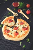 Γίνοντη πίτσα της Margherita κατ' οίκον Τοπ άποψη σχετικά με το σκοτεινό πίνακα στοκ φωτογραφίες Γίνοντη πίτσα της Margherita κατ' οίκον Τοπ άποψη σχετικά με το σκοτεινό πίνακα στοκ φωτογραφίες