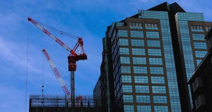 Γερανοί στο κτήριο στην επιχειρησιακή πόλη απόθεμα βίντεο Γερανοί στο κτήριο στην επιχειρησιακή πόλη απόθεμα βίντεο