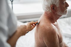 Γιατρός που ελέγχει την αναπνοή του γενειοφόρου ηληκιωμένου στοκ φωτογραφία με δικαίωμα ελεύθερης χρήσης Γιατρός που ελέγχει την αναπνοή του γενειοφόρου ηληκιωμένου στοκ φωτογραφία με δικαίωμα ελεύθερης χρήσης