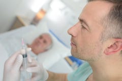 Γιατρός που προετοιμάζει την έγχυση για τον ασθενή στο νοσοκομειακό κρεβάτι στοκ φωτογραφίες Γιατρός που προετοιμάζει την έγχυση για τον ασθενή στο νοσοκομειακό κρεβάτι στοκ φωτογραφίες