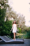 Γοητευτικό ελκυστικό πρότυπο κοριτσιών brunette μακρυμάλλους χαμόγελου ευτυχές σε έναν άσπρο περίπατο φορεμάτων από τον ποταμό στοκ φωτογραφία με δικαίωμα ελεύθερης χρήσης Γοητευτικό ελκυστικό πρότυπο κοριτσιών brunette μακρυμάλλους χαμόγελου ευτυχές σε έναν άσπρο περίπατο φορεμάτων από τον ποταμό στοκ φωτογραφία με δικαίωμα ελεύθερης χρήσης