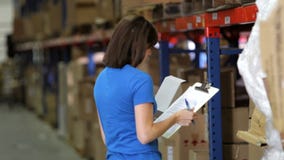 Γυναίκα εργαζόμενος με την περιοχή αποκομμάτων στην αποθήκη εμπορευμάτων απόθεμα βίντεο Γυναίκα εργαζόμενος με την περιοχή αποκομμάτων στην αποθήκη εμπορευμάτων απόθεμα βίντεο