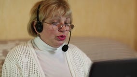 Γυναίκα με τα ακουστικά με τις συζητήσεις μικροφώνων σε έναν πελάτη μέσω του υπολογιστή απόθεμα βίντεο Γυναίκα με τα ακουστικά με τις συζητήσεις μικροφώνων σε έναν πελάτη μέσω του υπολογιστή απόθεμα βίντεο