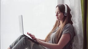 Γυναίκα με τα ακουστικά που λειτουργούν στο lap-top στο σπίτι φιλμ μικρού μήκους Γυναίκα με τα ακουστικά που λειτουργούν στο lap-top στο σπίτι φιλμ μικρού μήκους