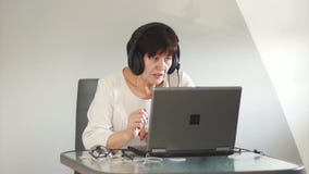 Γυναίκα με τα ακουστικά με τις συζητήσεις μικροφώνων σε έναν πελάτη μέσω του υπολογιστή Η γυναίκα με το PC επικοινωνεί μέσω του s απόθεμα βίντεο Γυναίκα με τα ακουστικά με τις συζητήσεις μικροφώνων σε έναν πελάτη μέσω του υπολογιστή Η γυναίκα με το PC επικοινωνεί μέσω του s απόθεμα βίντεο