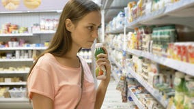 Γυναίκα που επιλέγει τα γαλακτοκομικά προϊόντα στο ψυγείο στο τμήμα παντοπωλείων λεωφόρου αγορών στοκ εικόνα Γυναίκα που επιλέγει τα γαλακτοκομικά προϊόντα στο ψυγείο στο τμήμα παντοπωλείων λεωφόρου αγορών στοκ εικόνα