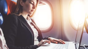 Γυναίκα που εργάζεται χρησιμοποιώντας το lap-top διακινούμενη με το αεροπλάνο στοκ εικόνα Γυναίκα που εργάζεται χρησιμοποιώντας το lap-top διακινούμενη με το αεροπλάνο στοκ εικόνα