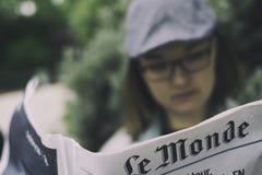 Γυναίκα που διαβάζει τη γαλλική εφημερίδα, Le Monde στοκ εικόνα με δικαίωμα ελεύθερης χρήσης Γυναίκα που διαβάζει τη γαλλική εφημερίδα, Le Monde στοκ εικόνα με δικαίωμα ελεύθερης χρήσης