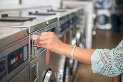 Γυναίκα που κάνει την πληρωμή που βάζει το τέταρτο laundromat πλύσης στο πλυντήριο μηχανών δημόσια Στοκ Φωτογραφία Γυναίκα που κάνει την πληρωμή που βάζει το τέταρτο laundromat πλύσης στο πλυντήριο μηχανών δημόσια Στοκ Φωτογραφία