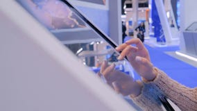 Γυναίκα που χρησιμοποιεί τη διαλογική επίδειξη οθονών επαφής στην έκθεση τεχνολογίας απόθεμα βίντεο Γυναίκα που χρησιμοποιεί τη διαλογική επίδειξη οθονών επαφής στην έκθεση τεχνολογίας απόθεμα βίντεο