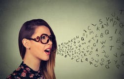 Γυναίκα στα γυαλιά που μιλούν με τις επιστολές αλφάβητου που βγαίνουν από το στόμα της στοκ φωτογραφία με δικαίωμα ελεύθερης χρήσης Γυναίκα στα γυαλιά που μιλούν με τις επιστολές αλφάβητου που βγαίνουν από το στόμα της στοκ φωτογραφία με δικαίωμα ελεύθερης χρήσης