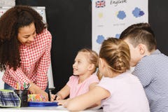 Δάσκαλος που βοηθά τα παιδιά κατά τη διάρκεια του μαθήματος στοκ φωτογραφία με δικαίωμα ελεύθερης χρήσης Δάσκαλος που βοηθά τα παιδιά κατά τη διάρκεια του μαθήματος στοκ φωτογραφία με δικαίωμα ελεύθερης χρήσης