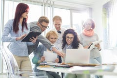 Δημιουργικό businesspeople χαμόγελου που λειτουργεί στο lap-top στο γραφείο στην αρχή Στοκ Εικόνα Δημιουργικό businesspeople χαμόγελου που λειτουργεί στο lap-top στο γραφείο στην αρχή Στοκ Εικόνα