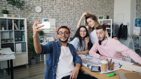 Δημιουργικός επιχειρηματίας που παίρνει selfie με την επιχειρησιακή ομάδα στο σύγχρονο γραφείο απόθεμα βίντεο Δημιουργικός επιχειρηματίας που παίρνει selfie με την επιχειρησιακή ομάδα στο σύγχρονο γραφείο απόθεμα βίντεο