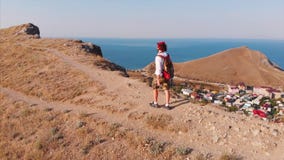 Διακινούμενο άτομο με ένα σακίδιο πλάτης και μια κάμερα, που περπατά μέσω των βουνών, με μια μεγάλη άποψη των βουνών και φιλμ μικρού μήκους Διακινούμενο άτομο με ένα σακίδιο πλάτης και μια κάμερα, που περπατά μέσω των βουνών, με μια μεγάλη άποψη των βουνών και φιλμ μικρού μήκους