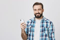 Διαφήμιση και έννοια τεχνολογίας Όμορφο ευρωπαϊκό αρσενικό πρότυπο smartphone εκμετάλλευσης υπό εξέταση χαμογελώντας cheerfuly στοκ εικόνες Διαφήμιση και έννοια τεχνολογίας Όμορφο ευρωπαϊκό αρσενικό πρότυπο smartphone εκμετάλλευσης υπό εξέταση χαμογελώντας cheerfuly στοκ εικόνες