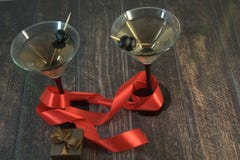 Δύο martini γυαλιά με τις ελιές, με την ερυθρά κορδέλλα, την μπλε ορχιδέα και σε έναν ξύλινο πίνακα στοκ εικόνες με δικαίωμα ελεύθερης χρήσης Δύο martini γυαλιά με τις ελιές, με την ερυθρά κορδέλλα, την μπλε ορχιδέα και σε έναν ξύλινο πίνακα στοκ εικόνες με δικαίωμα ελεύθερης χρήσης