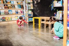 Δύο αδελφές που φορούν τα ίδια φωτεινά φορέματα που έχουν τη διασκέδαση στη βιβλιοθήκη παιδιών στοκ εικόνες με δικαίωμα ελεύθερης χρήσης Δύο αδελφές που φορούν τα ίδια φωτεινά φορέματα που έχουν τη διασκέδαση στη βιβλιοθήκη παιδιών στοκ εικόνες με δικαίωμα ελεύθερης χρήσης