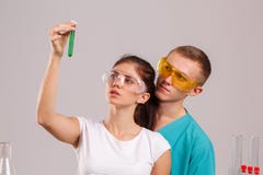 Δύο βοηθοί κρατούν στα χέρια τους και εξετάζουν μια μικρή φιάλη γυαλιού με ένα πράσινο υγρό στοκ εικόνα με δικαίωμα ελεύθερης χρήσης Δύο βοηθοί κρατούν στα χέρια τους και εξετάζουν μια μικρή φιάλη γυαλιού με ένα πράσινο υγρό στοκ εικόνα με δικαίωμα ελεύθερης χρήσης