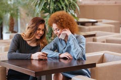 Δύο ευτυχείς γυναίκες που χρησιμοποιούν thir smartphones στον καφέ και το γέλιο στοκ φωτογραφία με δικαίωμα ελεύθερης χρήσης Δύο ευτυχείς γυναίκες που χρησιμοποιούν thir smartphones στον καφέ και το γέλιο στοκ φωτογραφία με δικαίωμα ελεύθερης χρήσης