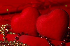 Δύο κόκκινες καρδιές σε ένα κόκκινο κλίμα με τις χρυσές και κόκκινες χάντρες στοκ φωτογραφία με δικαίωμα ελεύθερης χρήσης Δύο κόκκινες καρδιές σε ένα κόκκινο κλίμα με τις χρυσές και κόκκινες χάντρες στοκ φωτογραφία με δικαίωμα ελεύθερης χρήσης