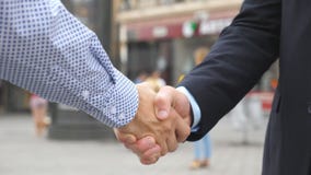 Δύο νέοι άνδρες συνάδελφοι που τινάζουν τα χέρια με το θολωμένο υπόβαθρο πόλεων Βέβαιοι επιχειρηματίες που χαιρετούν ο ένας τον ά φιλμ μικρού μήκους Δύο νέοι άνδρες συνάδελφοι που τινάζουν τα χέρια με το θολωμένο υπόβαθρο πόλεων Βέβαιοι επιχειρηματίες που χαιρετούν ο ένας τον ά φιλμ μικρού μήκους