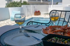 Δύο ποτήρια του άσπρων κρασιού και των γαρίδων στον πίνακα από τη λίμνη στοκ φωτογραφία με δικαίωμα ελεύθερης χρήσης Δύο ποτήρια του άσπρων κρασιού και των γαρίδων στον πίνακα από τη λίμνη στοκ φωτογραφία με δικαίωμα ελεύθερης χρήσης