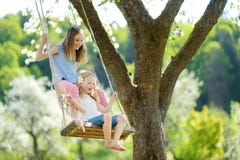 Δύο χαριτωμένες αδελφές που έχουν τη διασκέδαση σε μια ταλάντευση στον ανθίζοντας παλαιό κήπο δέντρων μηλιάς υπαίθρια την ηλιόλου στοκ φωτογραφίες με δικαίωμα ελεύθερης χρήσης Δύο χαριτωμένες αδελφές που έχουν τη διασκέδαση σε μια ταλάντευση στον ανθίζοντας παλαιό κήπο δέντρων μηλιάς υπαίθρια την ηλιόλου στοκ φωτογραφίες με δικαίωμα ελεύθερης χρήσης