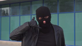 Εγκληματικός κλέφτης ή ληστής ατόμων στη μάσκα που παρουσιάζει χειρονομία κλήσης από τα δάχτυλά του απόθεμα βίντεο Εγκληματικός κλέφτης ή ληστής ατόμων στη μάσκα που παρουσιάζει χειρονομία κλήσης από τα δάχτυλά του απόθεμα βίντεο