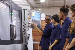 Εκπαιδευτικοί μαθητευόμενοι μηχανικών CNC στη μηχανή στοκ εικόνα με δικαίωμα ελεύθερης χρήσης Εκπαιδευτικοί μαθητευόμενοι μηχανικών CNC στη μηχανή στοκ εικόνα με δικαίωμα ελεύθερης χρήσης