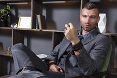 Εκφραστικός κοιτάξτε ενός όμορφου ατόμου σε ένα επιχειρησιακό κοστούμι, το οποίο κάθεται σε μια καρέκλα σε ένα πολυτελές διαμέρισ στοκ φωτογραφία με δικαίωμα ελεύθερης χρήσης Εκφραστικός κοιτάξτε ενός όμορφου ατόμου σε ένα επιχειρησιακό κοστούμι, το οποίο κάθεται σε μια καρέκλα σε ένα πολυτελές διαμέρισ στοκ φωτογραφία με δικαίωμα ελεύθερης χρήσης
