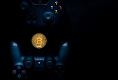 Ελεγκτές Playstation και Xbox δίπλα σε ένα φυσικό Bitcoin στοκ εικόνα Ελεγκτές Playstation και Xbox δίπλα σε ένα φυσικό Bitcoin στοκ εικόνα