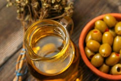 Ελιές με την πάπρικα σε ένα αναδρομικό κεραμικό κύπελλο ύφους, τον κλαδίσκο του ξηρού βασιλικού και τη στάμνα με το ελαιόλαδο στοκ φωτογραφία με δικαίωμα ελεύθερης χρήσης Ελιές με την πάπρικα σε ένα αναδρομικό κεραμικό κύπελλο ύφους, τον κλαδίσκο του ξηρού βασιλικού και τη στάμνα με το ελαιόλαδο στοκ φωτογραφία με δικαίωμα ελεύθερης χρήσης