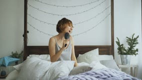 Ελκυστική εύθυμη γυναίκα που χορεύει και που τραγουδά με τη χτένα όπως τη συνεδρίαση μικροφώνων στο κρεβάτι στο σπίτι φιλμ μικρού μήκους Ελκυστική εύθυμη γυναίκα που χορεύει και που τραγουδά με τη χτένα όπως τη συνεδρίαση μικροφώνων στο κρεβάτι στο σπίτι φιλμ μικρού μήκους