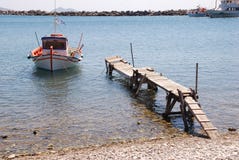 Ελληνικό αλιευτικό σκάφος που δένεται σε έναν ξεχαρβαλωμένο παλαιό λιμενοβραχίονα στοκ εικόνες με δικαίωμα ελεύθερης χρήσης Ελληνικό αλιευτικό σκάφος που δένεται σε έναν ξεχαρβαλωμένο παλαιό λιμενοβραχίονα στοκ εικόνες με δικαίωμα ελεύθερης χρήσης