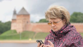 Ενήλικος τουρίστας γυναικών που κρατά ένα smartphone υπαίθρια απόθεμα βίντεο Ενήλικος τουρίστας γυναικών που κρατά ένα smartphone υπαίθρια απόθεμα βίντεο