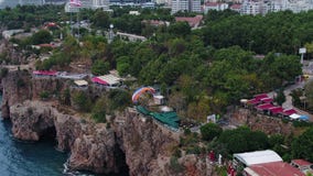 Εναέριος μετά από τα ανεμόπτερα πέρα από τη θάλασσα με την άποψη των βουνών και πράσινος φιλμ μικρού μήκους Εναέριος μετά από τα ανεμόπτερα πέρα από τη θάλασσα με την άποψη των βουνών και πράσινος φιλμ μικρού μήκους