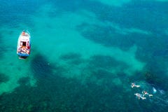 Εναέριος πυροβολισμός της τυρκουάζ λιμνοθάλασσας νερού στην καυτή θερινή ημέρα με τη λευκούς βάρκα και τους ανθρώπους που κολυμπο στοκ εικόνες Εναέριος πυροβολισμός της τυρκουάζ λιμνοθάλασσας νερού στην καυτή θερινή ημέρα με τη λευκούς βάρκα και τους ανθρώπους που κολυμπο στοκ εικόνες
