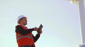 Ενεργειακός μηχανικός του ανεμόμυλου για να εργαστεί με την ταμπλέτα στο ηλιοβασίλεμα περιβαλλοντικός απόθεμα βίντεο Ενεργειακός μηχανικός του ανεμόμυλου για να εργαστεί με την ταμπλέτα στο ηλιοβασίλεμα περιβαλλοντικός απόθεμα βίντεο