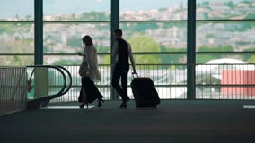 Επαγγελματικό ταξίδι, άνδρας και γυναίκα που περπατούν στην κυλιόμενη σκάλα στον αερολιμένα, φέρνοντας αποσκευές στοκ εικόνες με δικαίωμα ελεύθερης χρήσης Επαγγελματικό ταξίδι, άνδρας και γυναίκα που περπατούν στην κυλιόμενη σκάλα στον αερολιμένα, φέρνοντας αποσκευές στοκ εικόνες με δικαίωμα ελεύθερης χρήσης