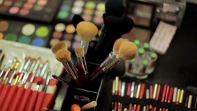 Επαγγελματικός καλλιτέχνης καλλυντικών makeup στον πίνακα Πολύχρωμο κραγιόν, σκιές και ποικίλες καλλυντικές βούρτσες φιλμ μικρού μήκους Επαγγελματικός καλλιτέχνης καλλυντικών makeup στον πίνακα Πολύχρωμο κραγιόν, σκιές και ποικίλες καλλυντικές βούρτσες φιλμ μικρού μήκους