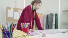 Επαγγελματικός όμορφος ασιατικός θηλυκός σχεδιαστής μόδας που εργάζεται με τα σκίτσα υφάσματος και που σύρει το σχέδιο ιματισμού φιλμ μικρού μήκους Επαγγελματικός όμορφος ασιατικός θηλυκός σχεδιαστής μόδας που εργάζεται με τα σκίτσα υφάσματος και που σύρει το σχέδιο ιματισμού φιλμ μικρού μήκους